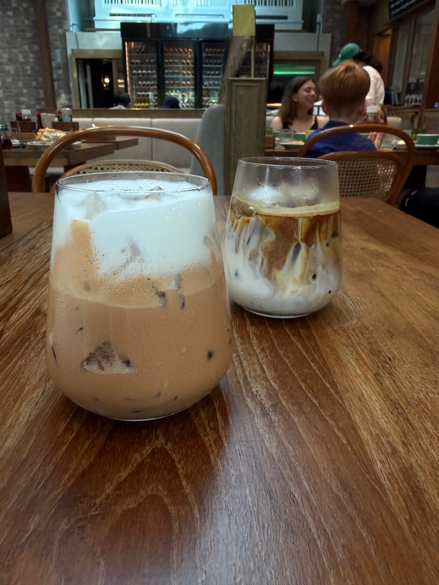 An iced cafe latte and a Thai tea latte on a wooden table at Fran's