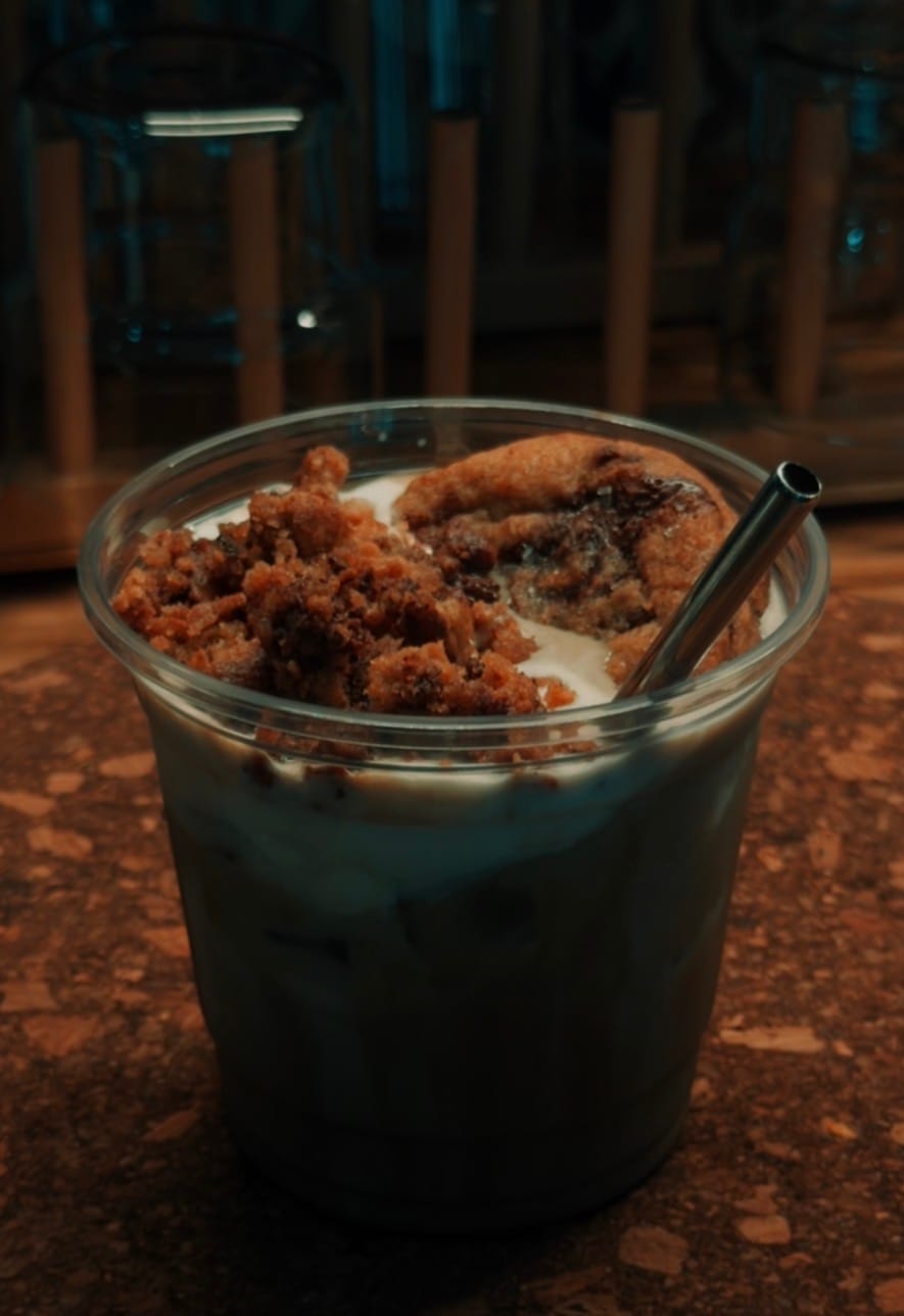 An iced drink topped with cookie crumble, moody lighting